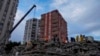 Люди и аварийные бригады ищут людей в разрушенном здании в Адане, Турция, в понедельник, 6 февраля 2023 года.  