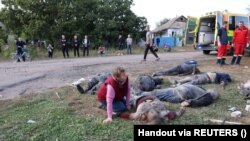 Жанчына плача каля целаў загінулых пасьля расейскага ўдару па вёсцы Гроза 5 кастрычніка 2023 году