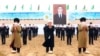Туркменские старейшины и чиновники на фоне изображения президента Сердара Бердымухамедова, который занял пост в марте 2022 года вместо отца