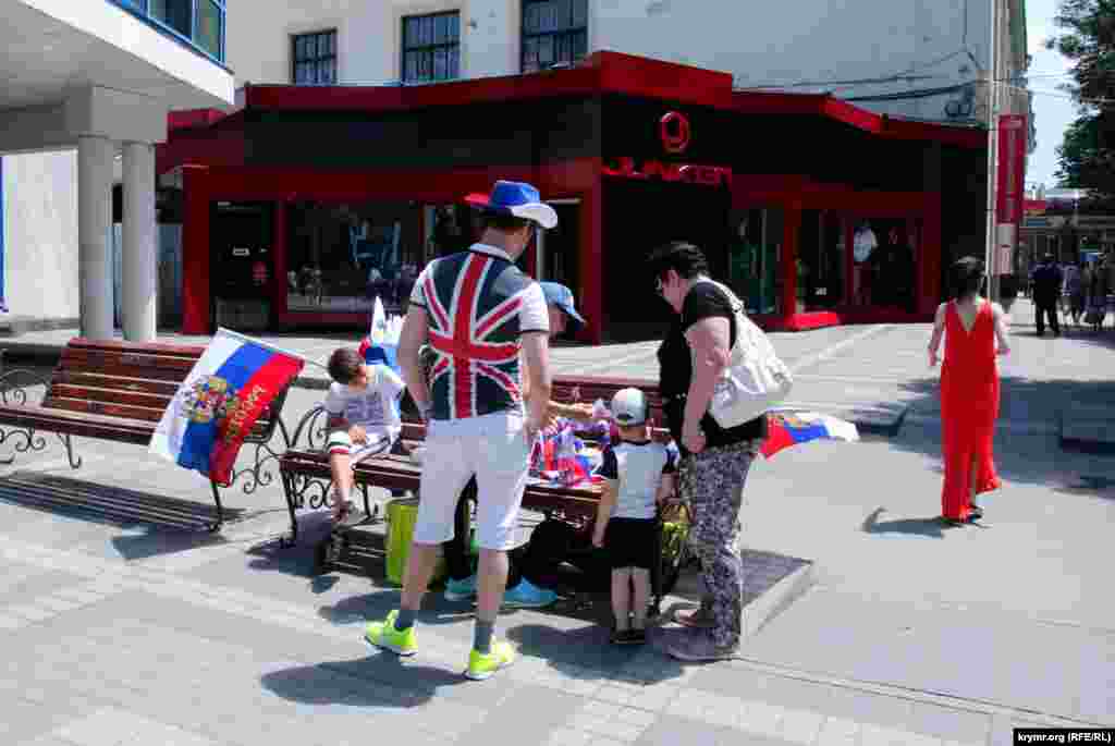 На центральних вулицях міста йшла торгівля сувенірною продукцією з російською символікою. Однак продавці не завжди були одягнені патріотично.