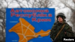 Militar rus lângă o hartă a Crimeei în orașul Kerci.