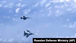 Истребитель Су-27 российских ВВС (внизу) маневрирует на фоне военного самолета НАТО F-18 над Балтийским морем. Архивное фото